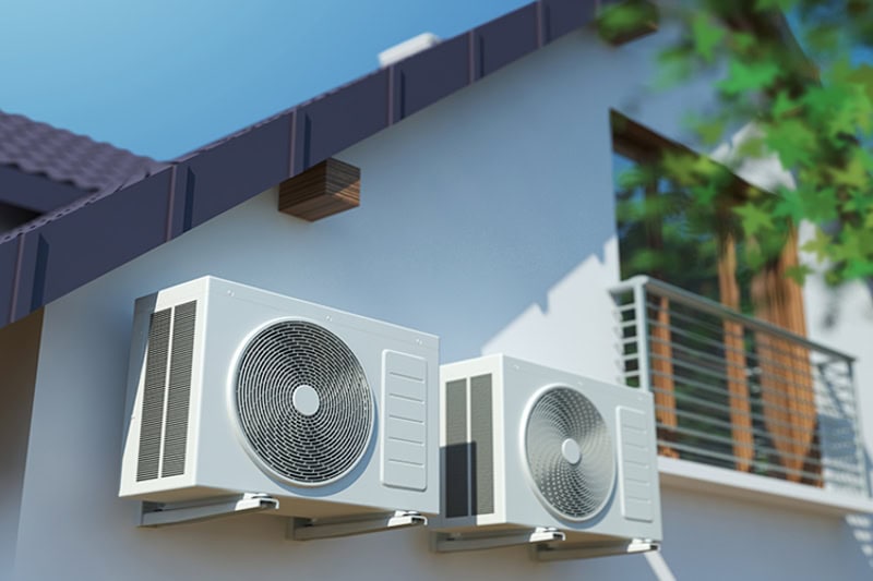 AC Definitions. Photo of two AC units mounted on the outside of a house.